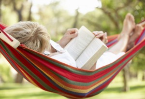 Senior Woman Relaxing In Hammock With Book